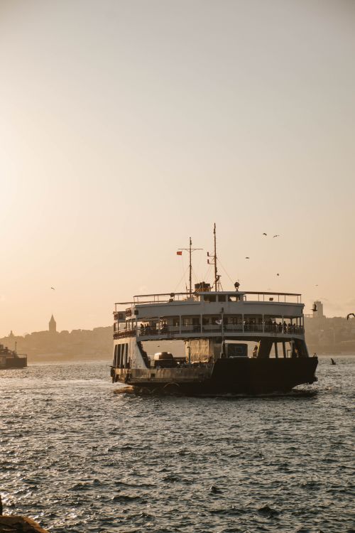 Free A ferry boat sails on the Bosphorus Strait during a serene sunset, capturing the essence of Istanbul's waterways. Stock Photo