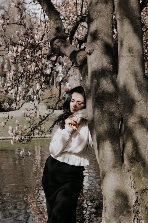 Woman in White Sweater leaning on to a Tree