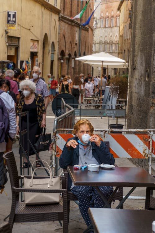 Elderly Woman Sitting Outside a Coffee Shop Drinking Coffee