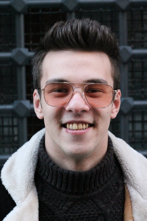 Man in Black Knitted Sweater and White Coat Wearing Brown Framed Sunglasses