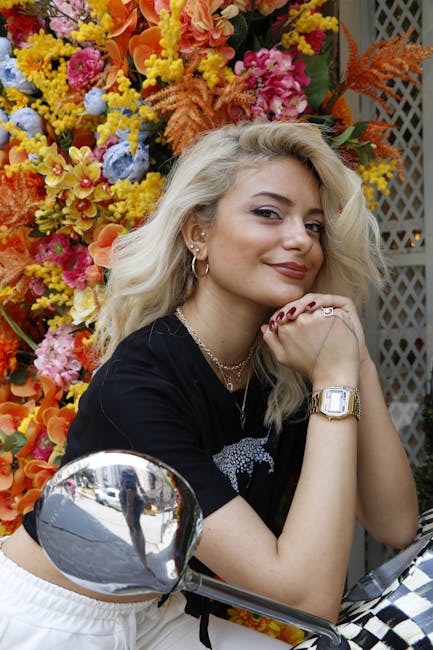 Charming portrait of a stylish woman posing against vibrant flower backdrop. Bright and cheerful setting.