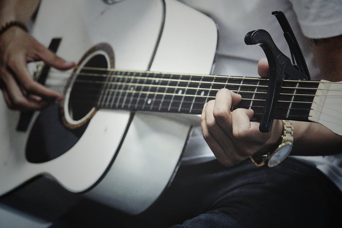 Free Man Holding a White Dreadnought Acoustic Guitar Stock Photo