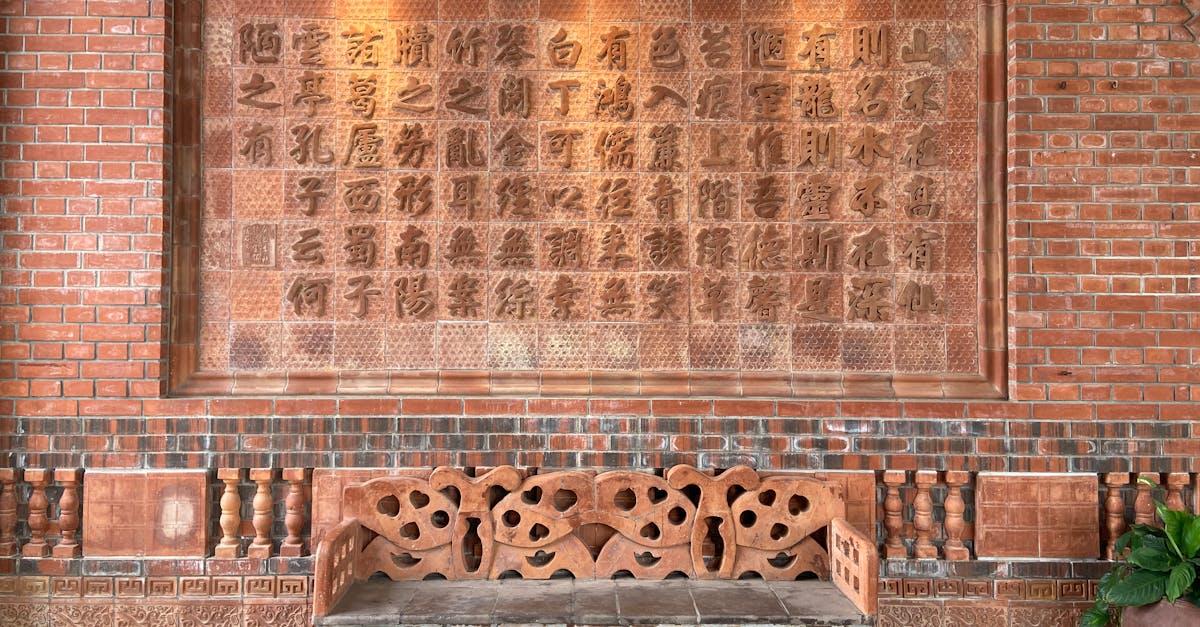 Rustic brick wall featuring intricate Chinese characters and a carved bench.
