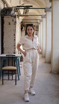 A stylish woman in a chic outfit poses confidently in an industrial corridor.