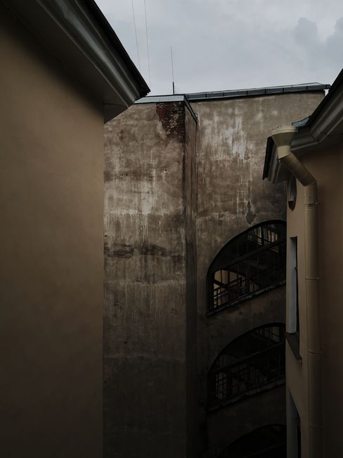 Aged, weathered building exterior with stained concrete wall and dark, moody tones.