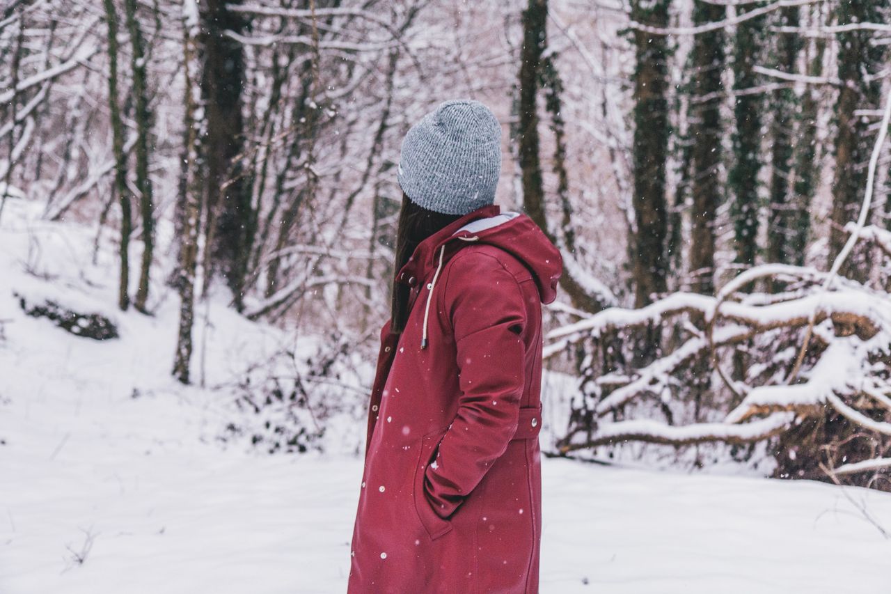 Woman in a red coat and gray beanie in a snowy forest