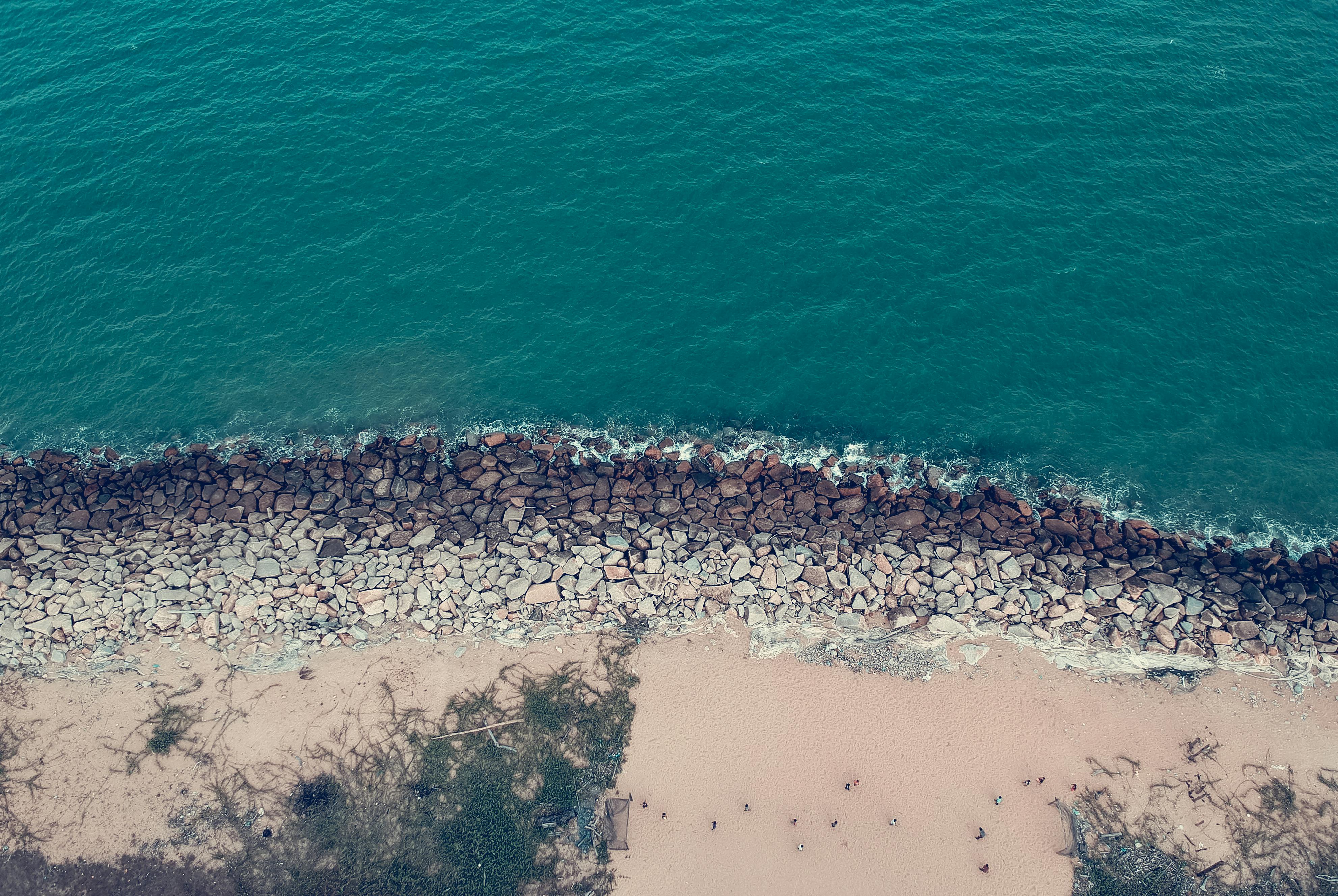 Scenic aerial view of a sandy beach with turquoise waters and rocky shoreline.