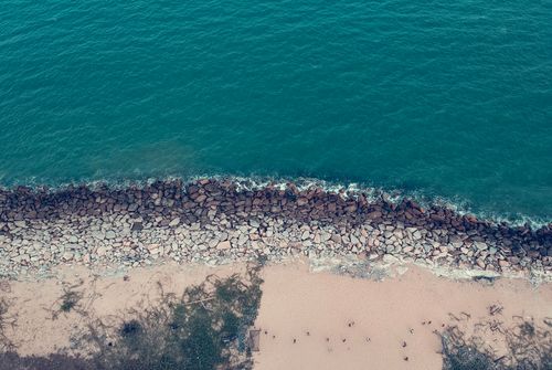 Free Scenic aerial view of a sandy beach with turquoise waters and rocky shoreline. Stock Photo