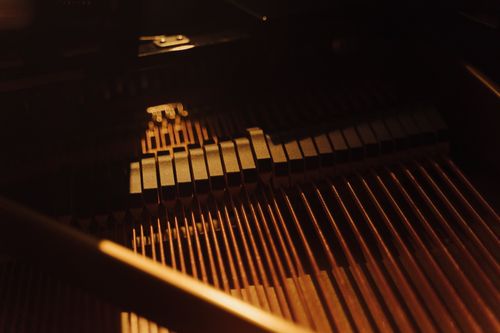 Free Close-up image of piano strings and hammers under warm, intimate lighting within a grand piano. Stock Photo