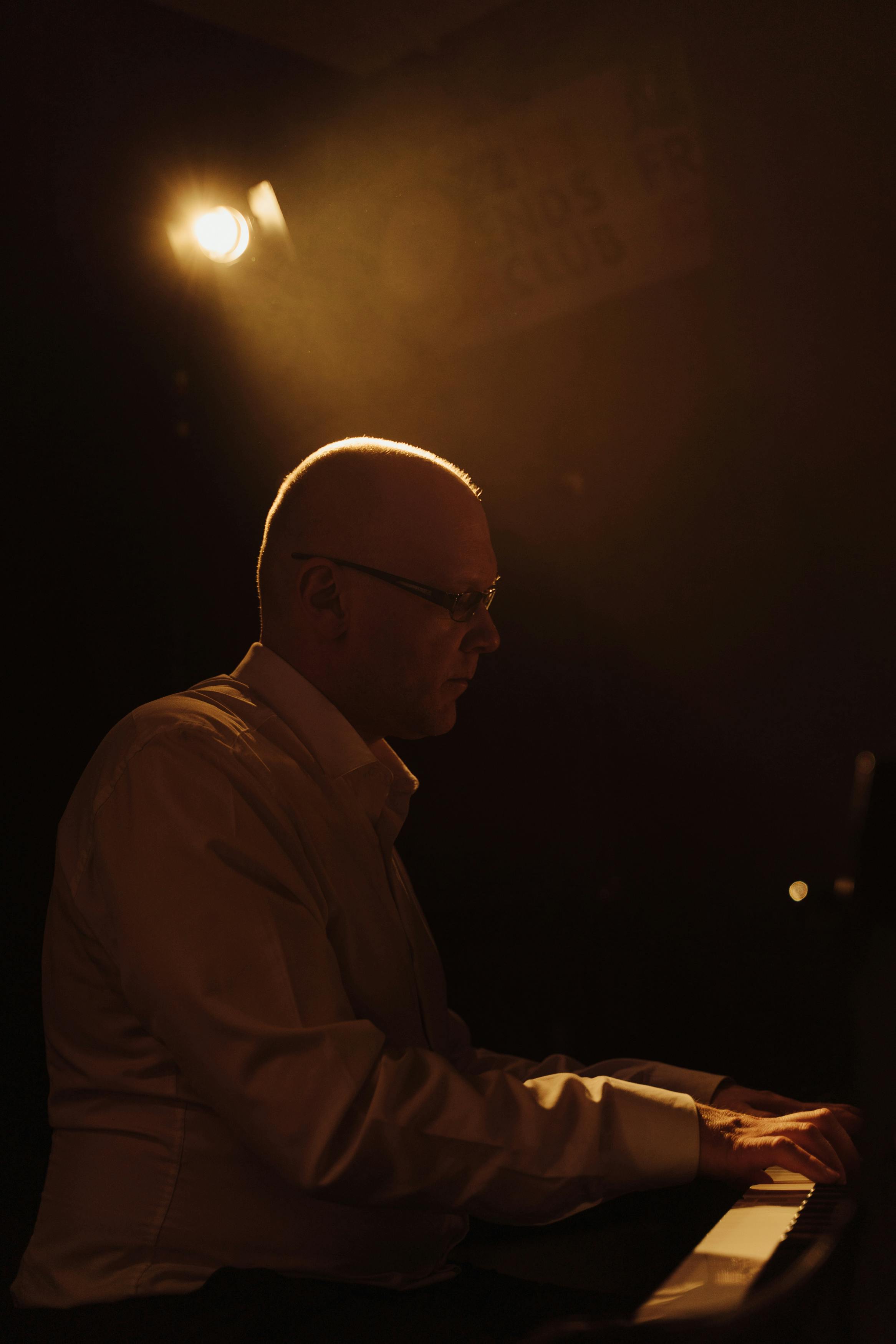 A focused pianist performing in a dimly lit, intimate setting, creating a moody and artistic atmosphere.