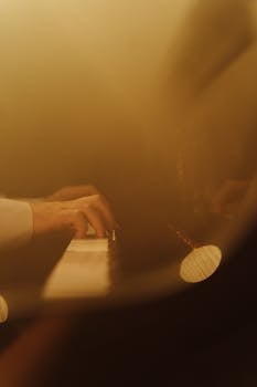 Close-up of hands playing a piano in a warm, artistic setting. Perfect for music and arts themes.