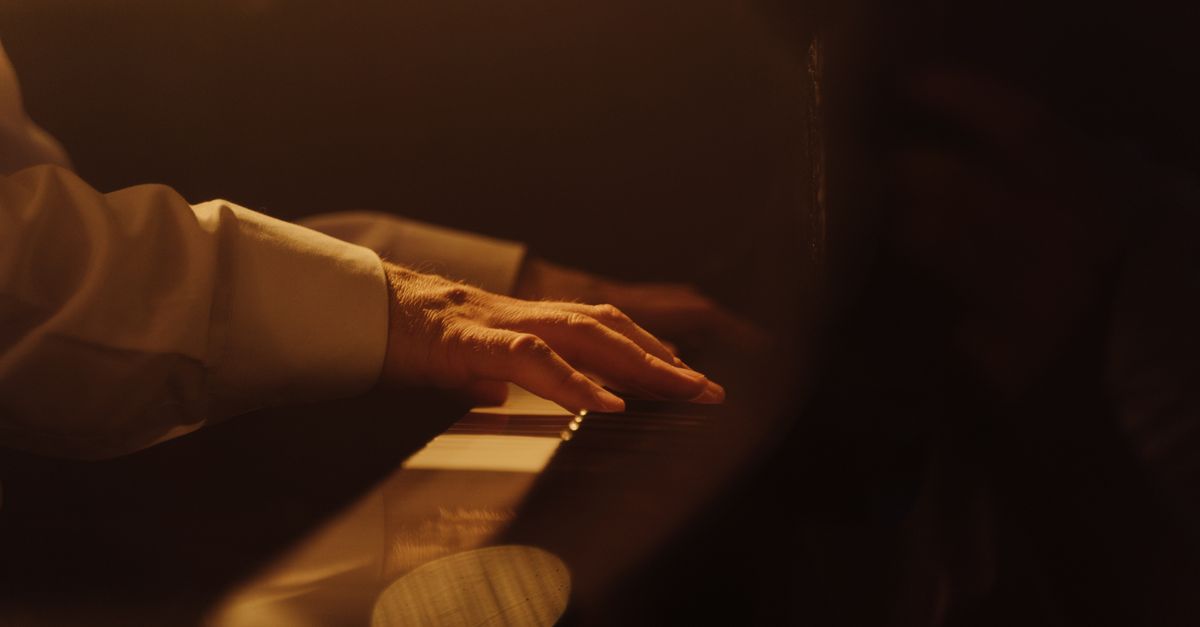 close-up of hands playing piano keys with worn-out instrument