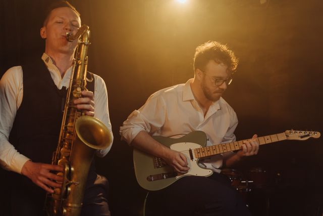 Jazz band playing saxophone and guitar under warm stage lighting