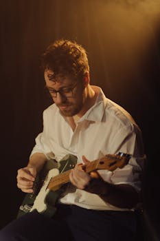 Male guitarist playing electric guitar in a warm spotlight setting, showcasing musical expression and concentration.