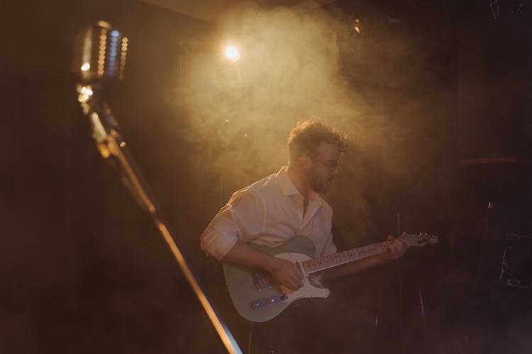 A Man In White Long Sleeves Playing Bass