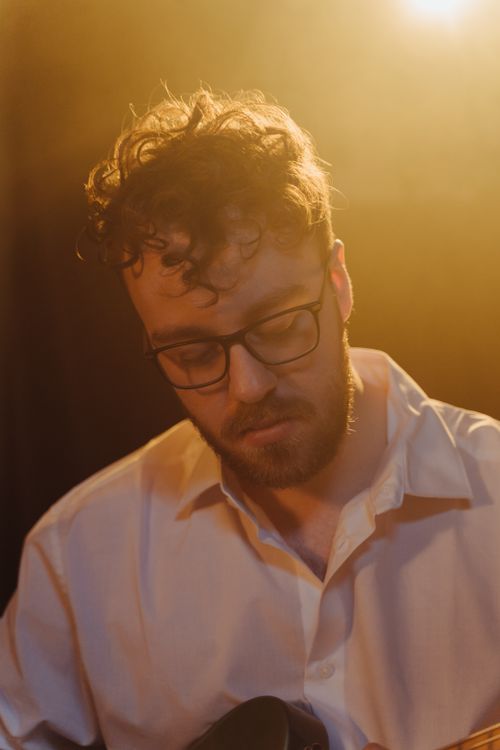 Free A thoughtful man with glasses in warm, moody lighting, creating a serene portrait. Stock Photo