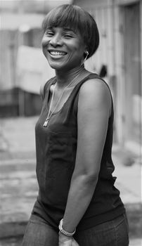 Black-and-white portrait of a smiling woman outdoors, exuding joy and confidence.
