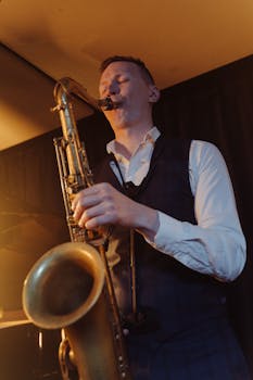 A saxophonist passionately performing jazz on stage under warm lighting.