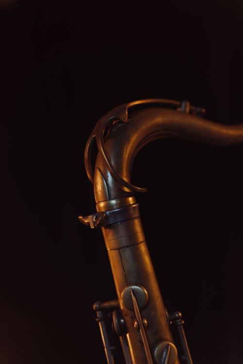Free Artistic close-up of a brass saxophone with warm lighting and deep shadows. Stock Photo