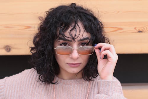 Close-Up Shot of a Curly-Haired Woman Wearing Sunglasses