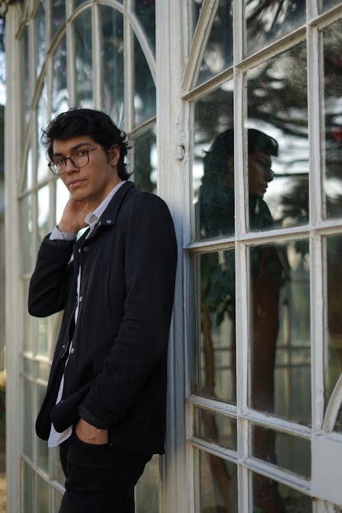 Free A Man in Black Suit Leaning on a Glass Window Stock Photo