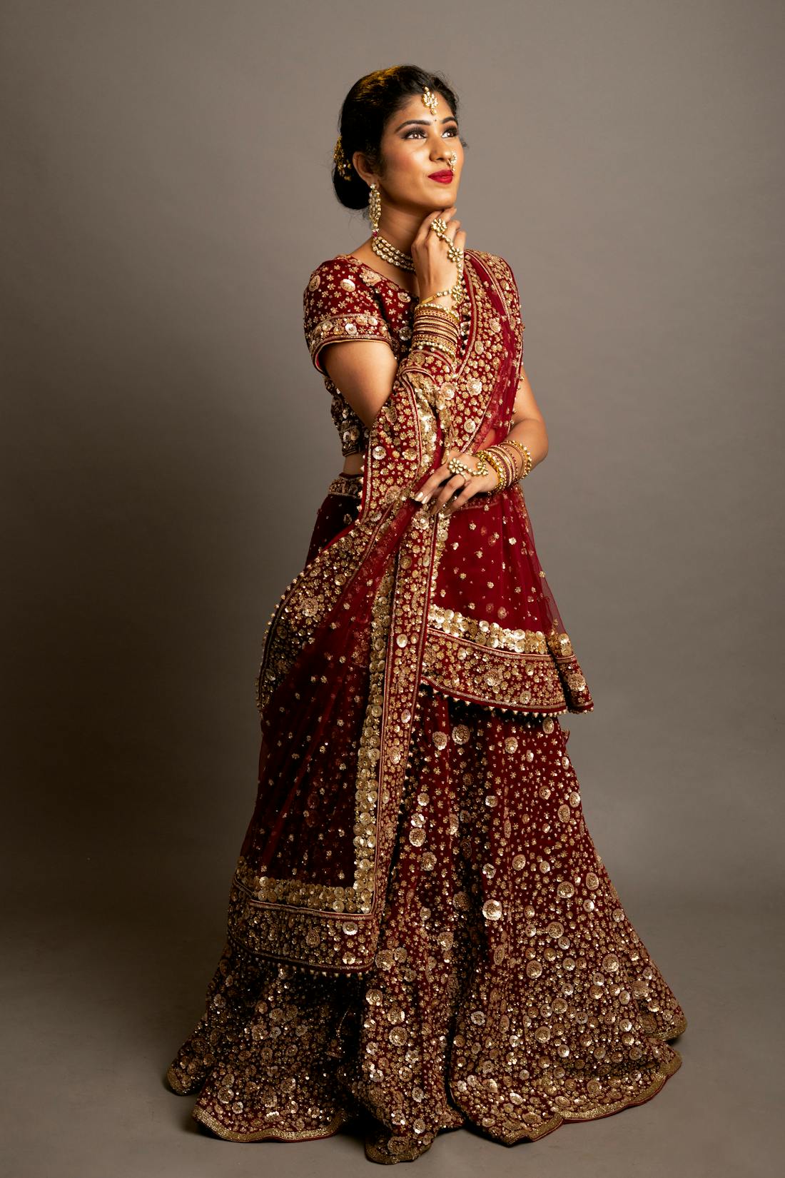 Red and gold lehenga styled with an embellished waist belt and layered dupatta