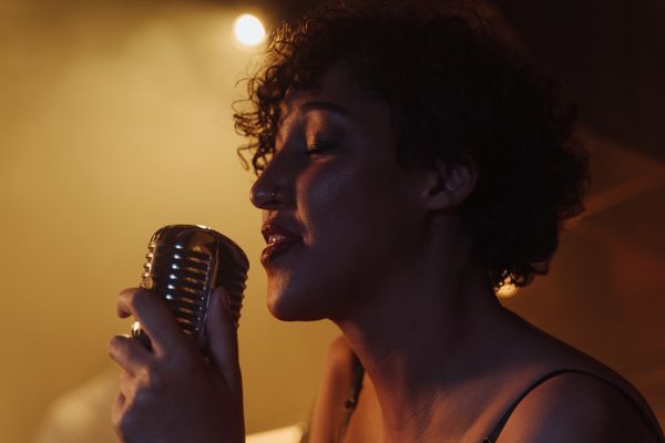 Vocalist singing into a vintage microphone under warm light — photo by cottonbro studio on Pexels