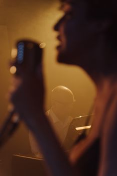 Blurred silhouette of a singer with a microphone on stage during a jazz performance.
