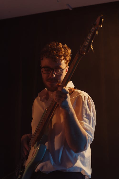 A Man in White Long Sleeves Playing Bass