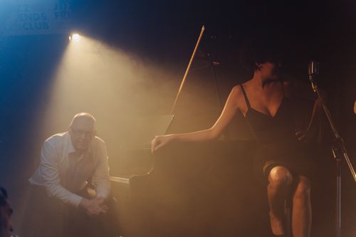 Free Moody jazz club performance featuring a pianist and singer on stage. Stock Photo