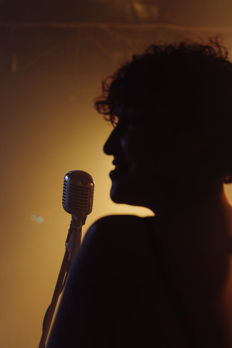 Silhouette of singer with vintage microphone in warm amber lighting