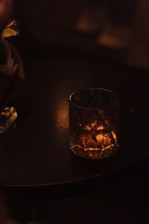Free Elegant whiskey glass on a dark table setting, casting a warm, moody ambiance. Stock Photo