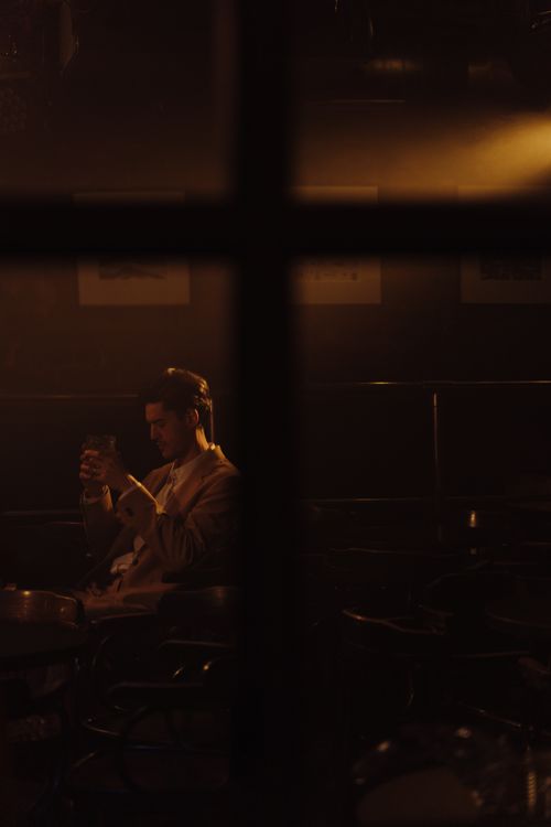 Free A contemplative man in a suit holding a drink in a dimly lit bar, creating a serene ambiance. Stock Photo