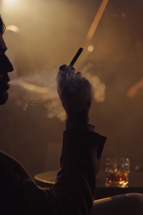 Free Moody silhouette of a man smoking indoors with dramatic lighting. Stock Photo