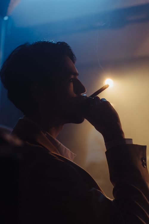 Free A man smokes a cigar in low light, creating a moody and atmospheric scene. Stock Photo