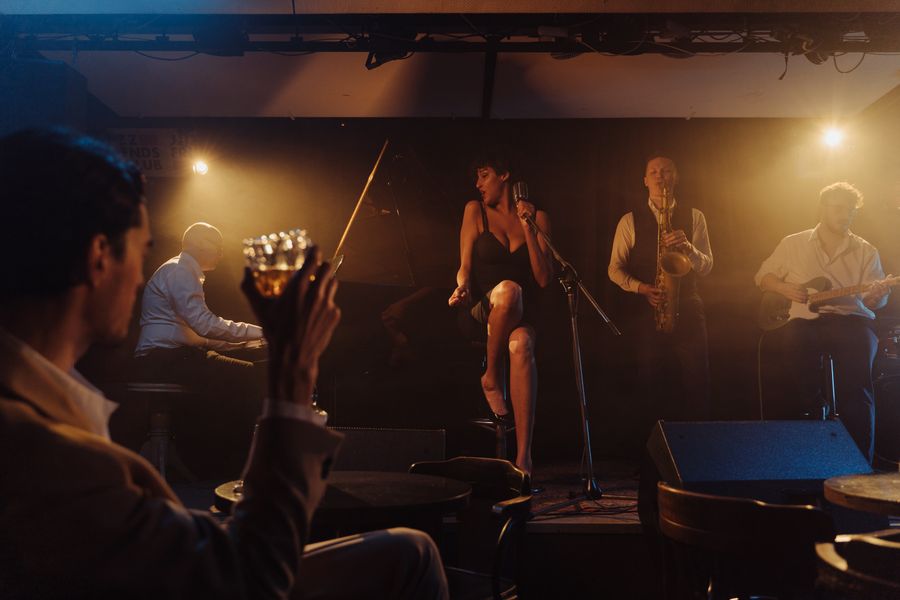 A band playing on a small stage in a low-lit bar, the singer close to the front row.