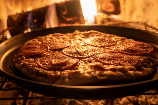 Close-up of pepperoni pizza baking in a wood-fired oven, capturing the warmth and mouthwatering details.