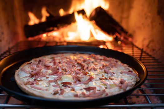 Delicious wood-fired pizza baking in a rustic oven with visible flames, perfect for food enthusiasts.