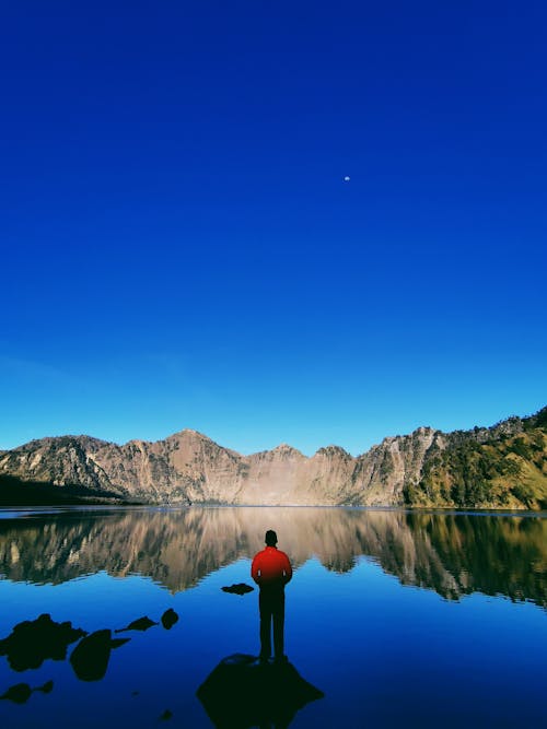Free A Person Standing on a Rock over a Lake  Stock Photo