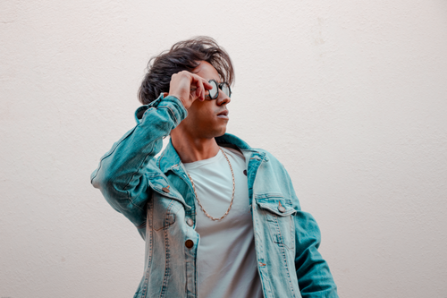 Free A man posing stylishly in denim jacket and sunglasses against a white background. Stock Photo