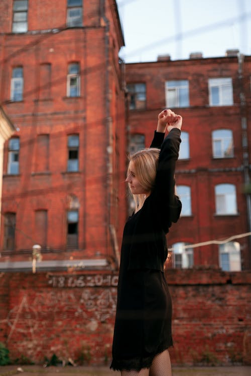 Woman in Black Long Sleeve Dress Standing Near a Building