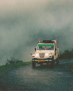 A rugged off-road vehicle moves through a rainy mountain road in Dwara, India.