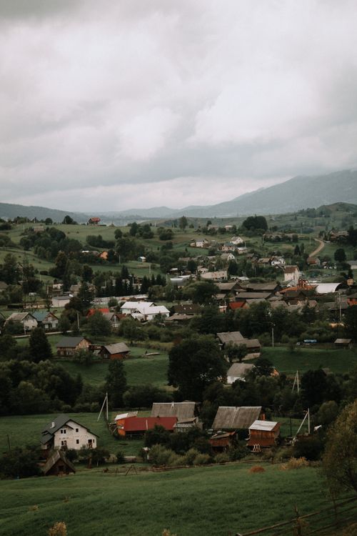 Free A serene mountain village landscape with houses and greenery under a cloudy sky. Stock Photo