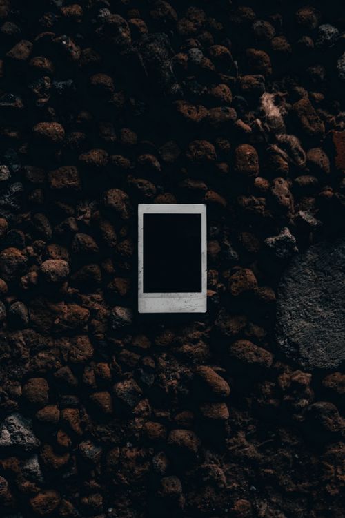Free Empty polaroid photo on a dark textured stone background, creating a mysterious and vintage feel. Stock Photo