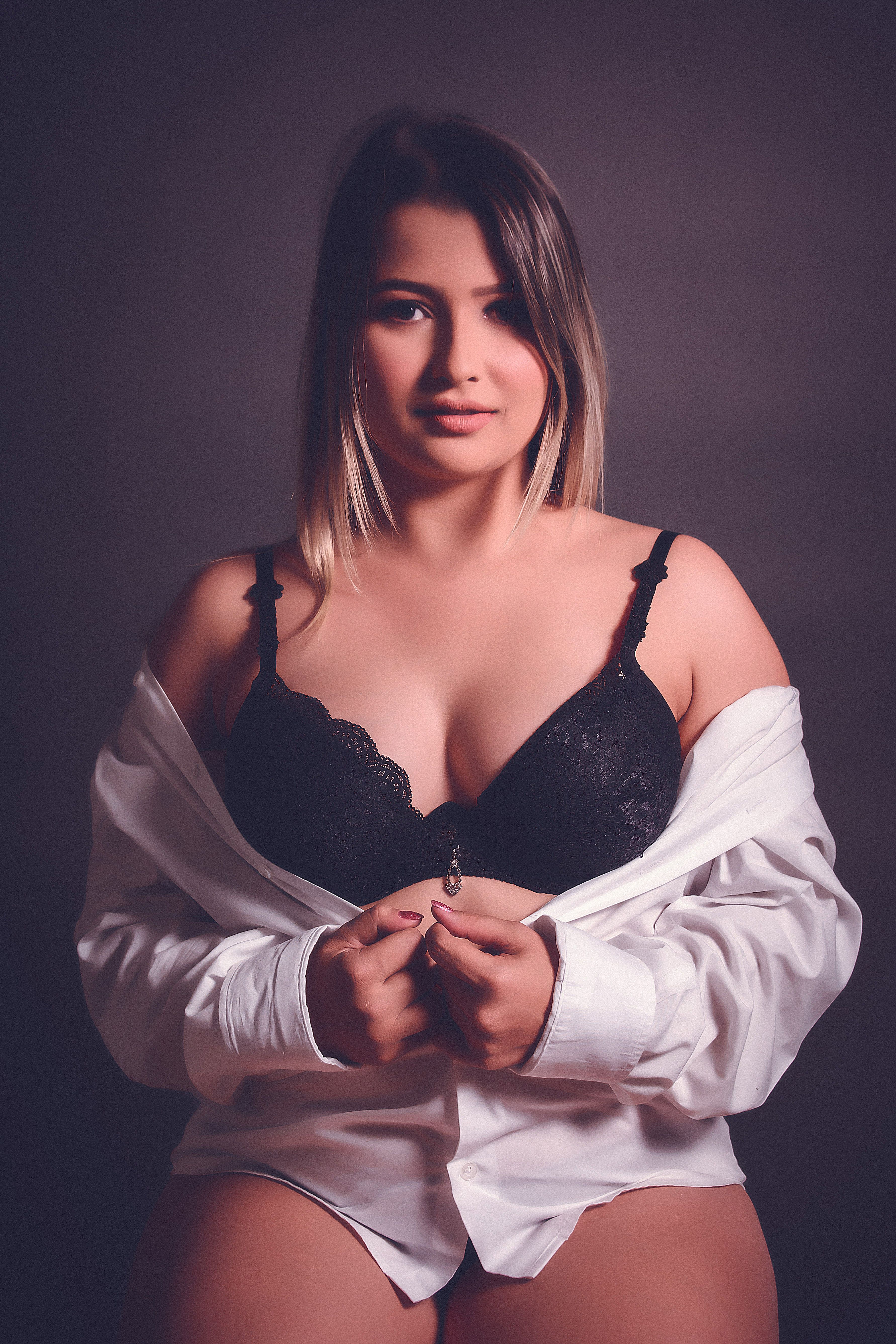 Sophisticated adult woman posing in black lingerie with a white shirt, exuding elegance and confidence.