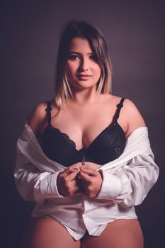 Sophisticated adult woman posing in black lingerie with a white shirt, exuding elegance and confidence.