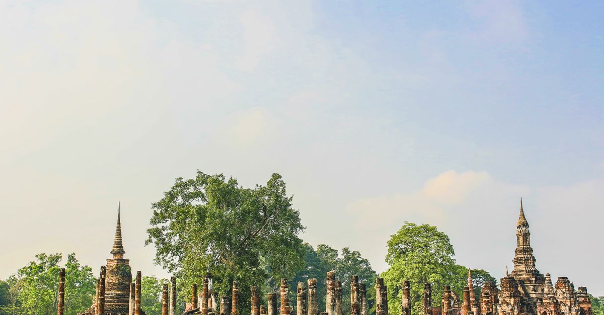 Wat Mahathat ruins reflected in lotus pond Sukhothai Thailand