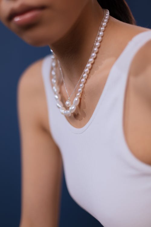 Woman in White Tank Top Wearing White Necklace