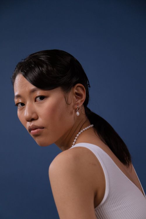 Free Side profile portrait of a woman against a blue background, showcasing elegant jewelry. Stock Photo