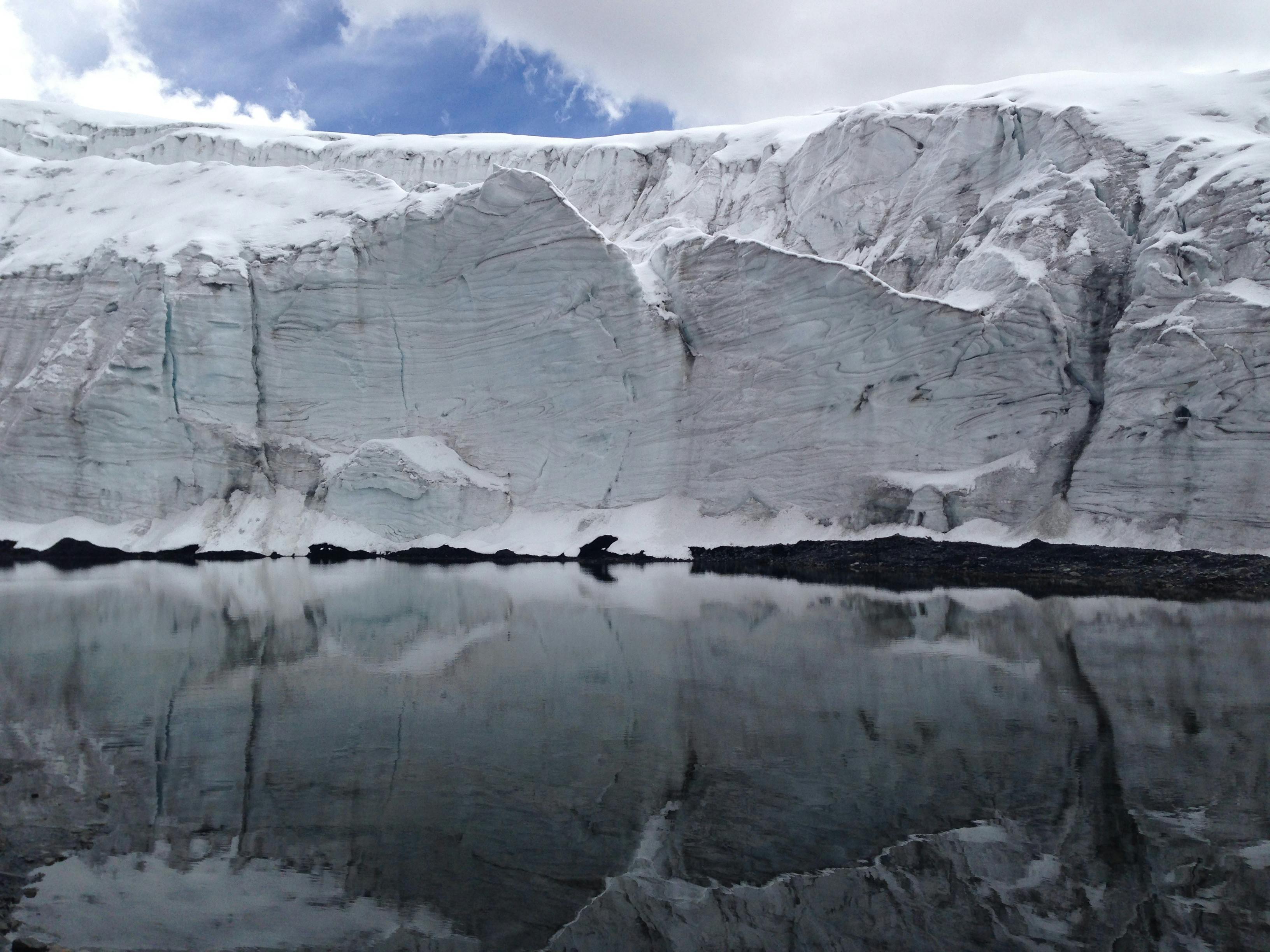 Prescription Goggle Inserts - A stunning glacier mirrors in calm water under a blue sky, showcasing serene natural beauty.